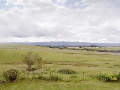 a field of green grass with a fence and trees at Townhead Mill in Dumfries