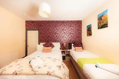 two beds in a small room with purple wallpaper at Cosy Central Apartment by the Meadows 4 in Edinburgh