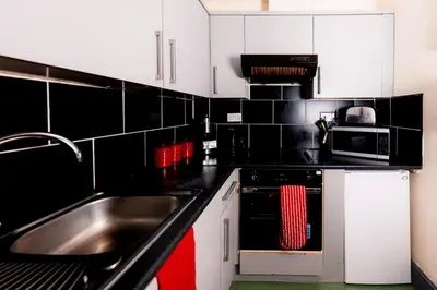 a kitchen with black and white cabinets and a sink at Cosy Central Apartment by the Meadows 4 in Edinburgh