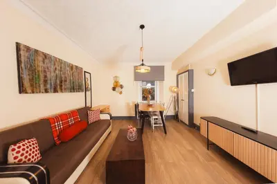 a living room with a couch and a flat screen tv at Cosy Central Apartment by the Meadows 4 in Edinburgh