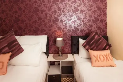 two beds in a room with purple wallpaper at Cosy Central Apartment by the Meadows 4 in Edinburgh