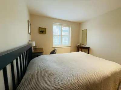 a bedroom with a large bed and a window at Stylish Two-Bedroom Flat with Garden Near Henley Town Centre in Moffat