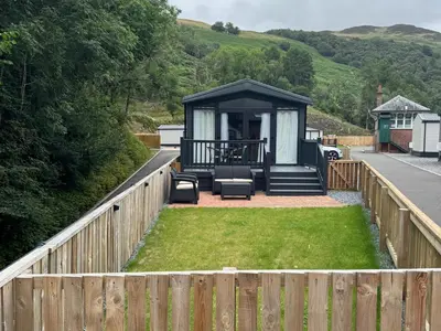 a gazebo with a fence and grass at Lime Tree Lodge in Crieff
