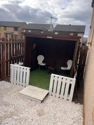 a backyard with two white chairs and a shed at Hutchison apartments in Edinburgh