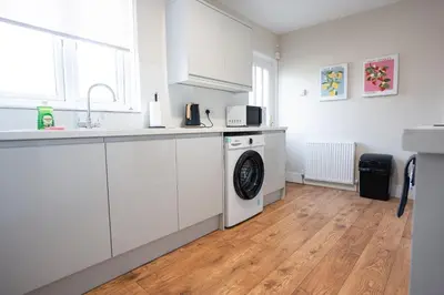 a kitchen with white cabinets and a washing machine at California House in Falkirk