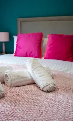 a bed with white towels on it with pink pillows at California House in Falkirk