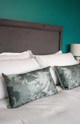 a bed with white sheets and pillows and a green wall at California House in Falkirk