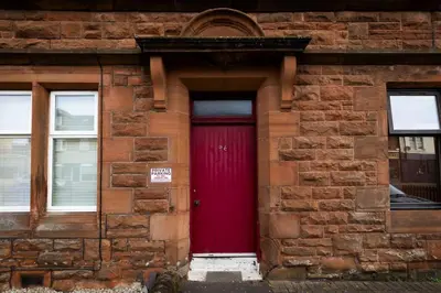a red door on the side of a brick building at Troon - Coastal Getaway in Troon