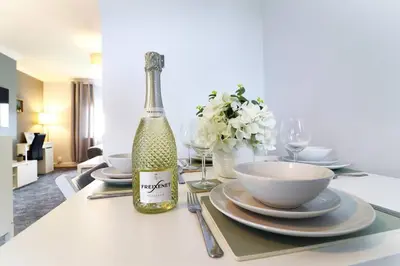 a bottle of wine sitting on a table with plates at Lovely 2 BR flat, sleeps 4 in Chapelhall