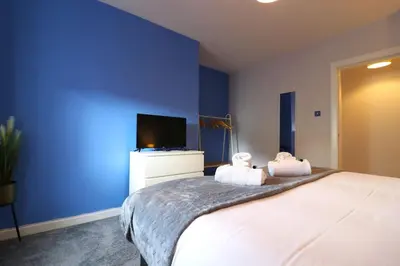 a bedroom with blue walls and a bed with two towels at Lovely 2 BR flat, sleeps 4 in Chapelhall