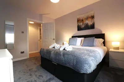 a bedroom with a large bed with two stuffed animals on it at Lovely 2 BR flat, sleeps 4 in Chapelhall