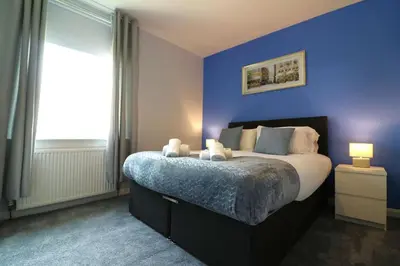 a bedroom with a large bed with a blue wall at Perfect 4 BR flat, sleeps 8 in Chapelhall