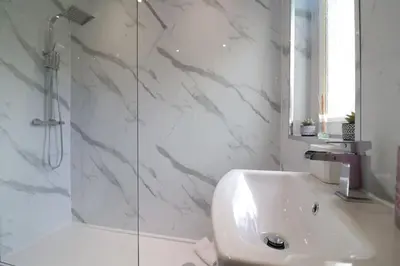a white bathroom with a sink and a shower at Perfect 4 BR flat, sleeps 8 in Chapelhall