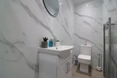 a white bathroom with a sink and a toilet at Perfect 4 BR flat, sleeps 8 in Chapelhall