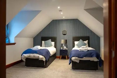 a bedroom with two beds with blue and white sheets at The Cottage at Barraston Farm in Glasgow