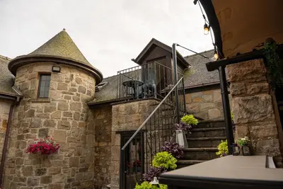 a stone house with a turret and stairs with flowers at Barraston Farm in Glasgow