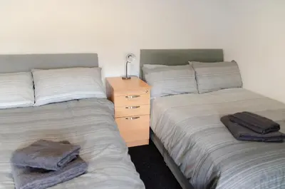 a bedroom with two beds and a dresser with towels at Beech Cottage in Armadale