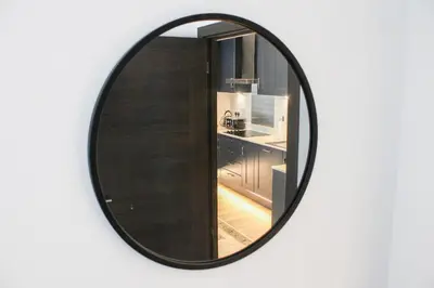 a round mirror on a wall with a kitchen at The Sunrise Den, Modern 2-Bed Apartment, Free Parking in Yarrow