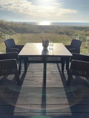 a table on a deck with two wine glasses on it at The Beach House in Moffat