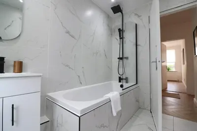 a white bathroom with a tub and a shower at Signature - Oak House in Coatbridge