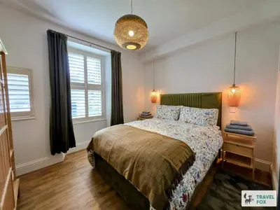 a bedroom with a bed and two windows at High Street Stay - Oban in Oban