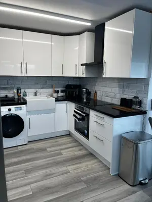 a white kitchen with white cabinets and a dishwasher at City Centre Apartment in Glasgow