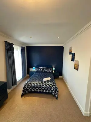 a bedroom with a bed and a blue wall at Fairholme Gardens House in Moffat