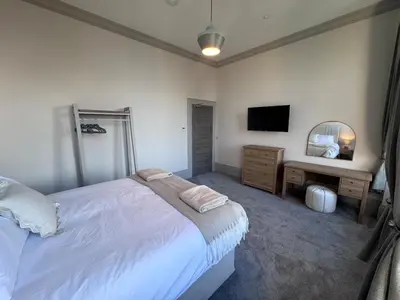 a bedroom with a bed and a desk and a television at Taobh na Mara - Macaulay Letting in Helensburgh