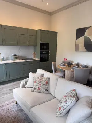 a living room with a couch and a kitchen at The Comet - Macaulay Letting in Helensburgh