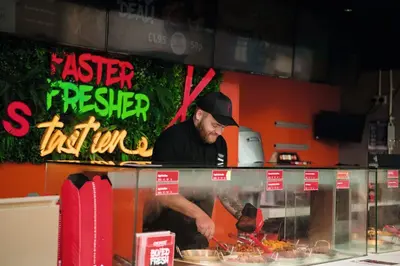 a man preparing food behind a counter in a restaurant at A&L Holiday Home Craigtara in Ayr