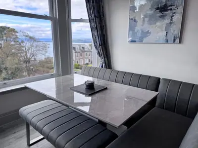a table and a bench in a room with a window at Abhaille Chluaidh - Macaulay Letting in Helensburgh