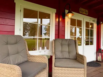 two wicker chairs sitting on the porch of a house at Stylish Cabin with Countryside Views and King Bed in Maybole
