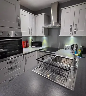 a kitchen with a dish drying rack in the sink at 3 Bedroom FM Homes & Apartments Wishaw Motherwell in Dalziel