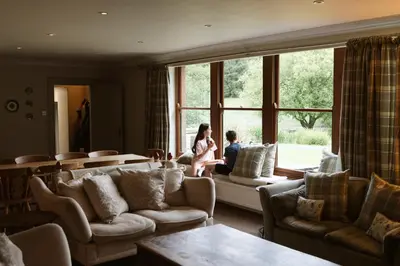 a woman and child sitting on a couch in a living room at The Coach House in Castle Douglas