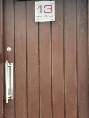 a sign on the side of a wooden building at Thistle Tide 13 Nelson Street Largs KA308LN 1st Floor in Largs