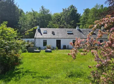 a white house with a yard with green grass at Rock Cottage in Isle of Arran