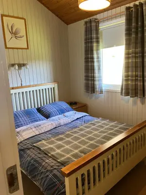a bedroom with a bed with blue sheets and a window at Golden Mary in Morenish