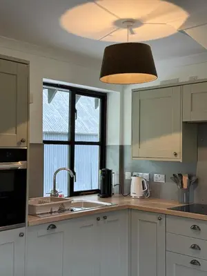 a kitchen with white cabinets and a light fixture at Highland Nook for 4 in Fort William