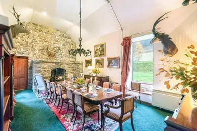 a dining room with a table and a stone fireplace at Glenogle Highland Estate Home in Lochearnhead
