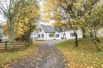 a driveway leading to a white house with a fence at Glenogle Highland Estate Home in Lochearnhead