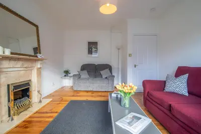 a living room with a red couch and a fireplace at Ashgrove House - 3 bedroom in Coatbridge