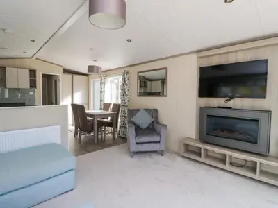 a living room with a television and a table with chairs at Altair Lodge in Crieff