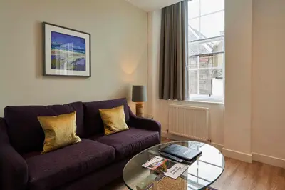 a living room with a purple couch and a glass table at Braid Apartments by Mansley in Edinburgh