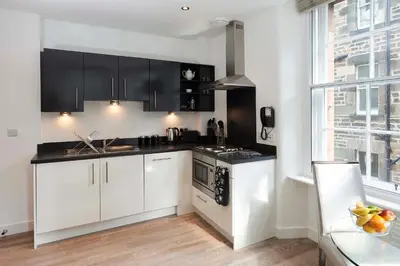 a kitchen with black and white cabinets and a window at Braid Apartments by Mansley in Edinburgh