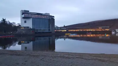 a building sitting next to a body of water at The Old Smiddy Cottage and Apartment in Balloch