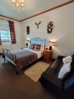 a bedroom with a bed and a couch at The Old Smiddy Cottage and Apartment in Balloch
