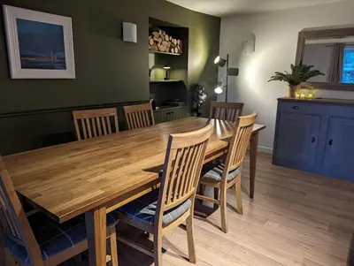 a dining room with a wooden table and chairs at Ashdale Cottage with Sauna, Plunge Pool, Games Room, Kit Drying Room in Isle of Arran