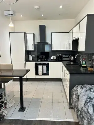 a kitchen with white cabinets and a table in it at Fantastic 1 Bed in Heart of Edinburgh in Edinburgh