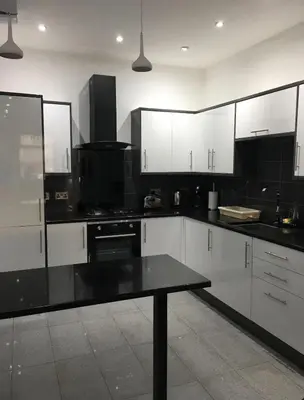 a kitchen with white cabinets and a black counter top at Fantastic 1 Bed in Heart of Edinburgh in Edinburgh