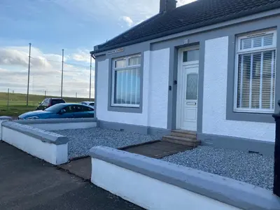 a white house with a front door and a driveway at Woodside Bungalow in Stevenston
